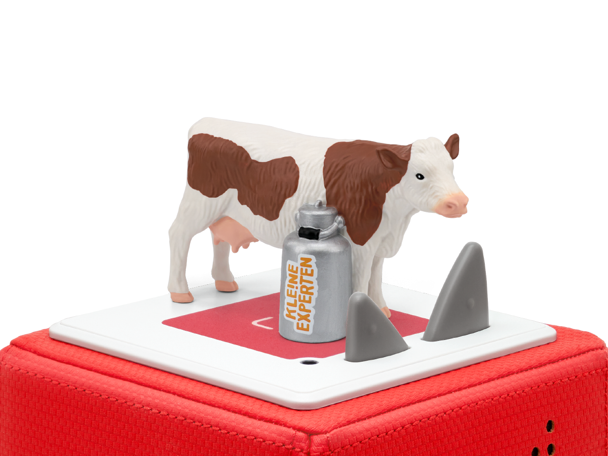 Nahaufnahme der TONIES KLE!NE EXPERTEN Figur, die Kühe auf einer grünen Wiese mittendrin umgibt