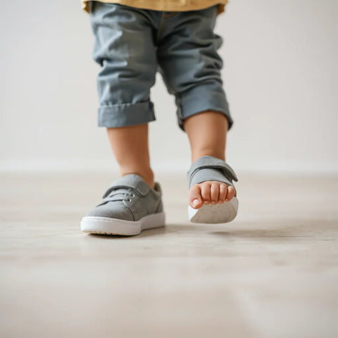 Kinderfüße in leichten, flexiblen Schuhen beim ersten sicheren Schritt auf hellem Boden