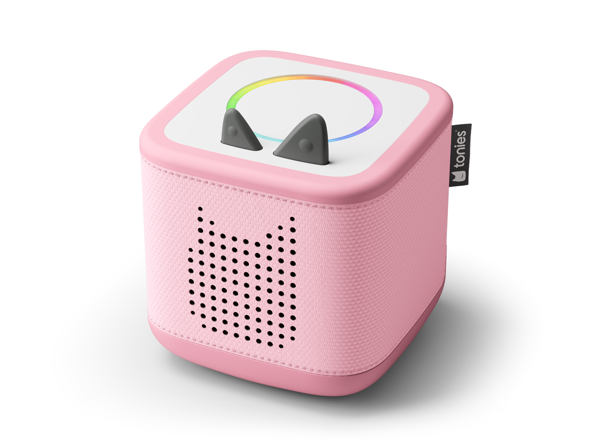 Kinderhände greifen nach der rosa Toniebox 2 mit abwischbarem Stoff und sanfter Beleuchtung