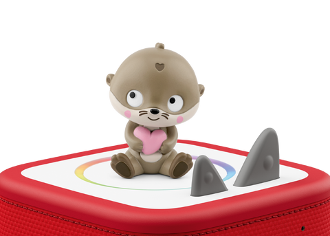 Vorderansicht einer TONIES-Figur: Kleiner Otter hält rosa Herz, sitzt auf rotem Tonies-Box-Deckel mit grauen Finnen.
