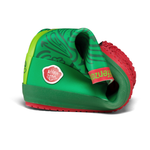 Seitenansicht des AFFENZAHN Gummistiefel Vegan Plashy FROSCH grün/rot mit Logo-Patch an der Seite und roter Sohle.