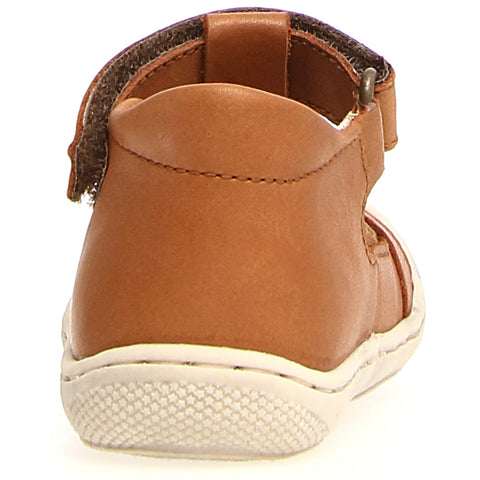 Child wearing NATURINO HALBSANDALE LANGEN - COGNAC sandal while playing at the beach