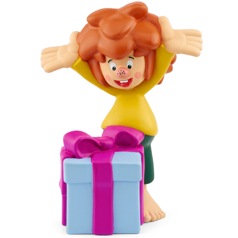 Tonies Figur Pumuckl Vorderansicht, gelbes Oberteil, grüne Hose, rotes Haar, vor blauem Geschenk mit pinkem Band