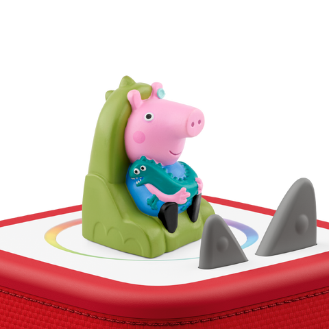 Vorderansicht: TONIES Figur – Peppa Pig sitzt auf grünem Dino auf roter Tonies-Box, blaues Outfit.