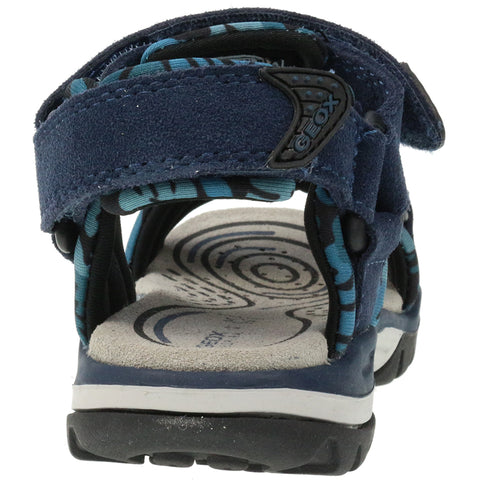 Child wearing GEOX Sandale BOREALIS J720RE in blau and türkis, walking on a sandy beach